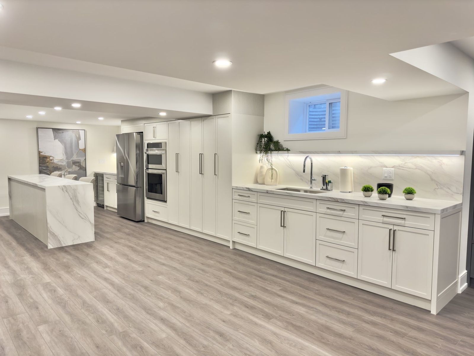 A finished kitchen with a marble island and walnut tall units